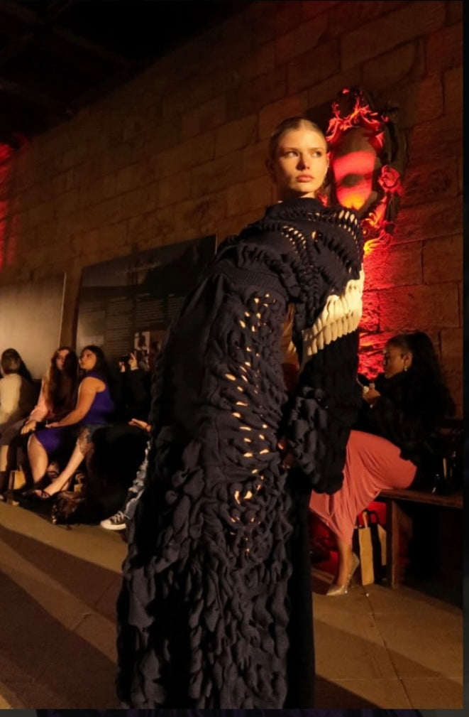 Model wearing the sculptural cutwork coat on the runway at a charity fashion show